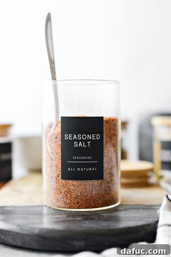 A jar of all-purpose seasoning salt on a wooden surface with a measuring spoon