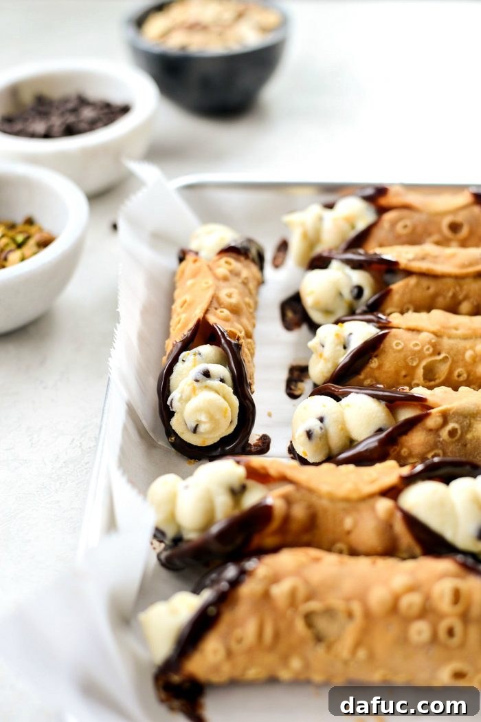 Piping ricotta filling into cannoli shells.