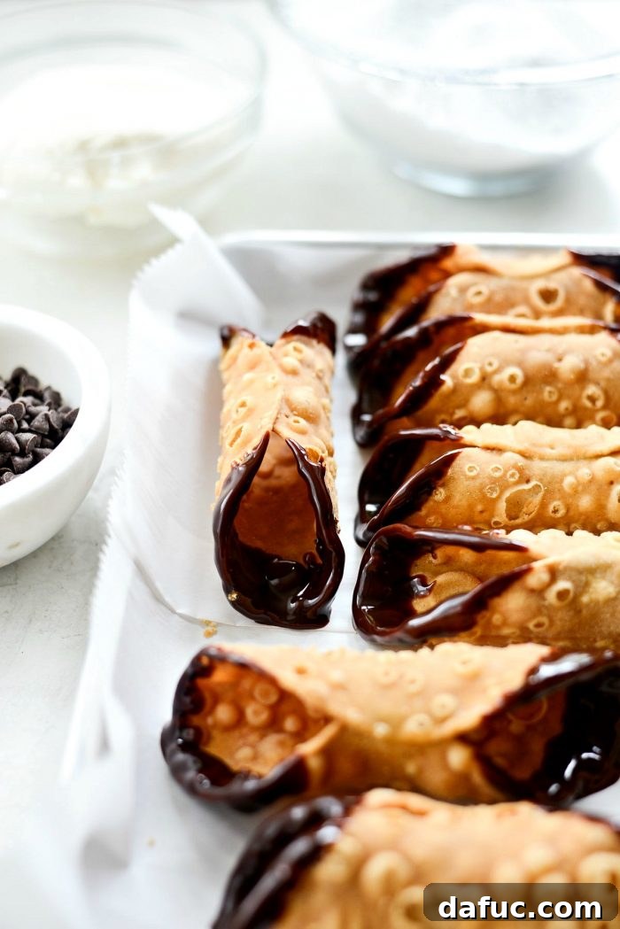 Dipping cannoli shells in espresso chocolate sauce.