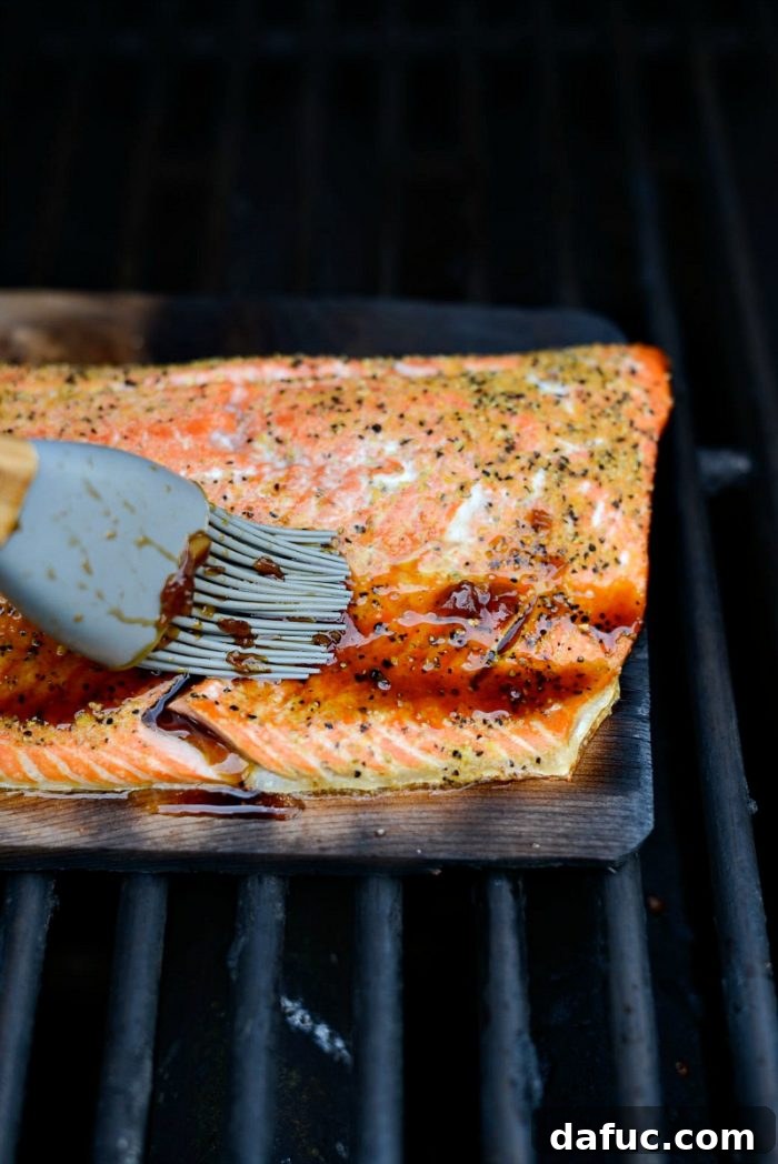 Signature Grilled Whiskey Glazed Cedar Plank Salmon 13 Salmon cooking on a cedar plank on the grill, lid closed