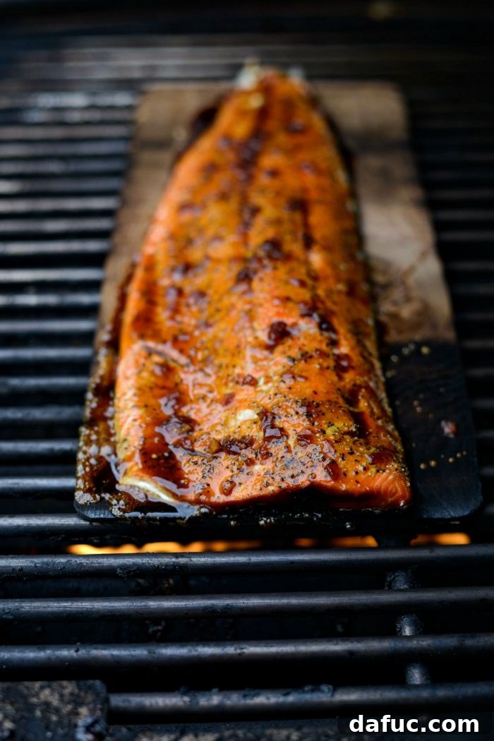 Signature Grilled Whiskey Glazed Cedar Plank Salmon 14 Salmon being brushed with whiskey glaze on the grill