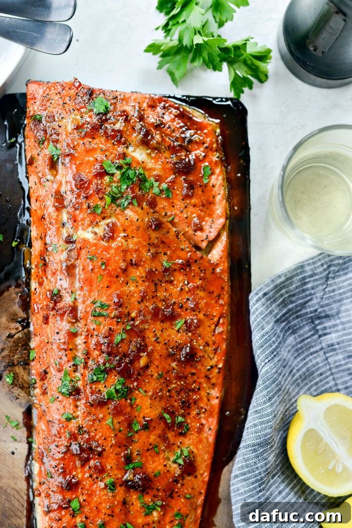 Signature Grilled Whiskey Glazed Cedar Plank Salmon 17 Slicing grilled salmon into portions on the cedar plank