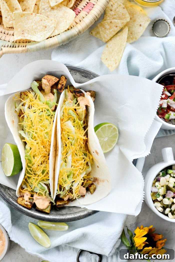 Spicy potato soft tacos arranged on a serving plate with lime wedges