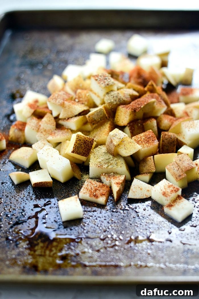 Close-up of potato cubes evenly spread on a baking sheet before roasting