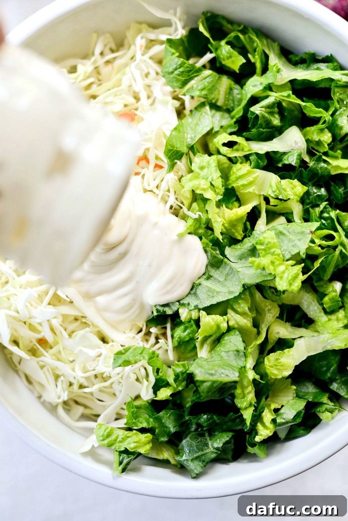 Zesty BBQ Chicken Slaw Summer Bowl 9 Shredded coleslaw mix and romaine lettuce being tossed in a large bowl