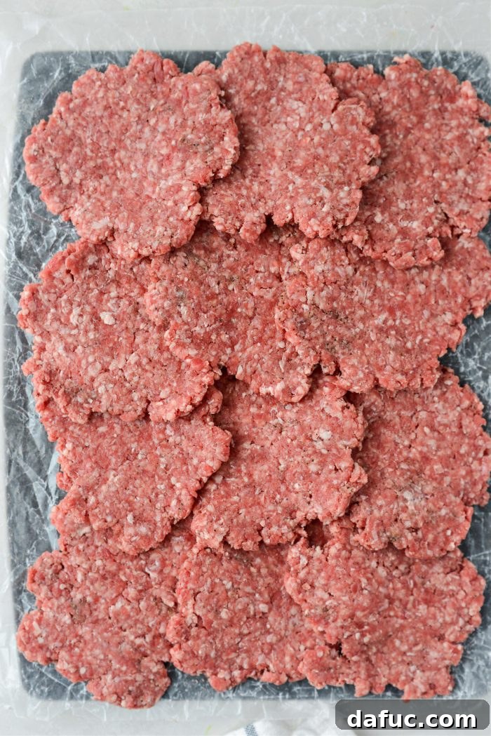 Mac Mini Bites 11 A ball of ground beef being flattened between two pieces of wax paper using a drinking glass.