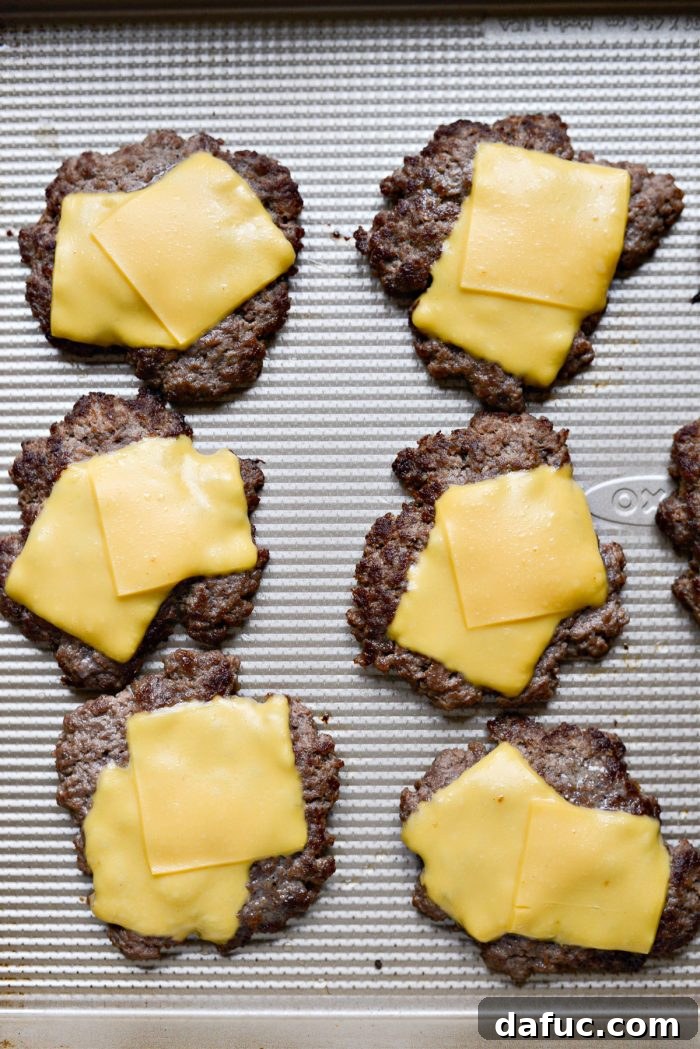Mac Mini Bites 14 Cooked burger patties with melted cheese being transferred to a plate after cooking.