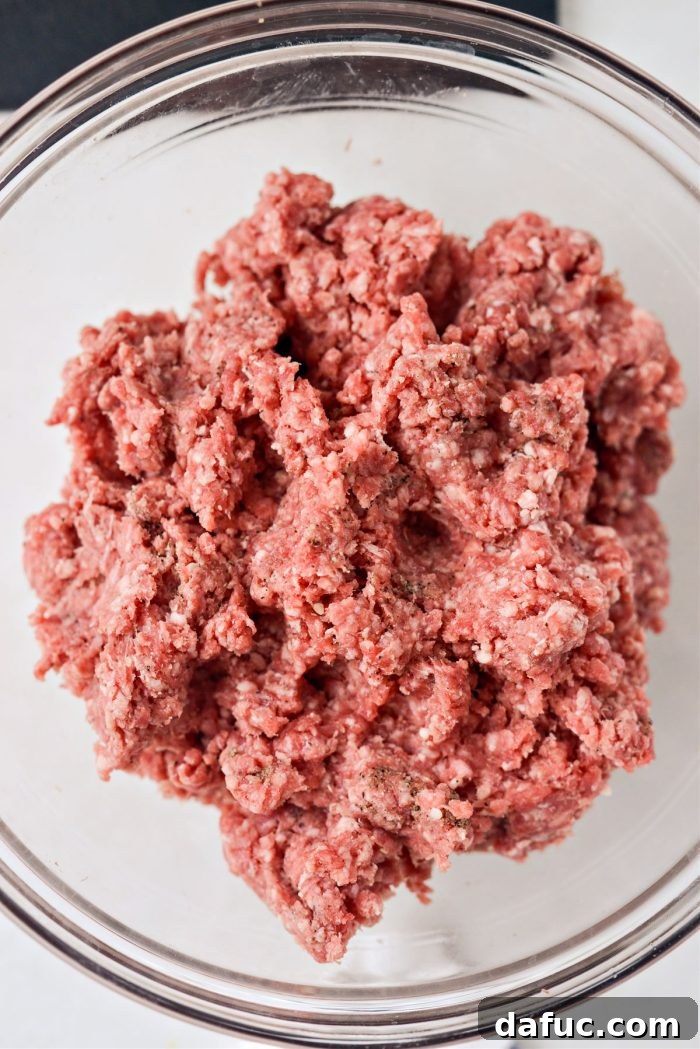 Mac Mini Bites 9 Hands mixing ground beef gently to combine seasonings without overworking the meat.