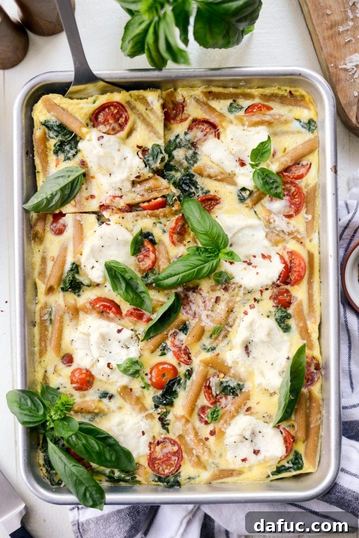 Mediterranean Sheet Pan Pasta Frittata 14 Sheet Pan Spinach Tomato Ricotta Pasta Frittata served with fresh basil and black pepper.