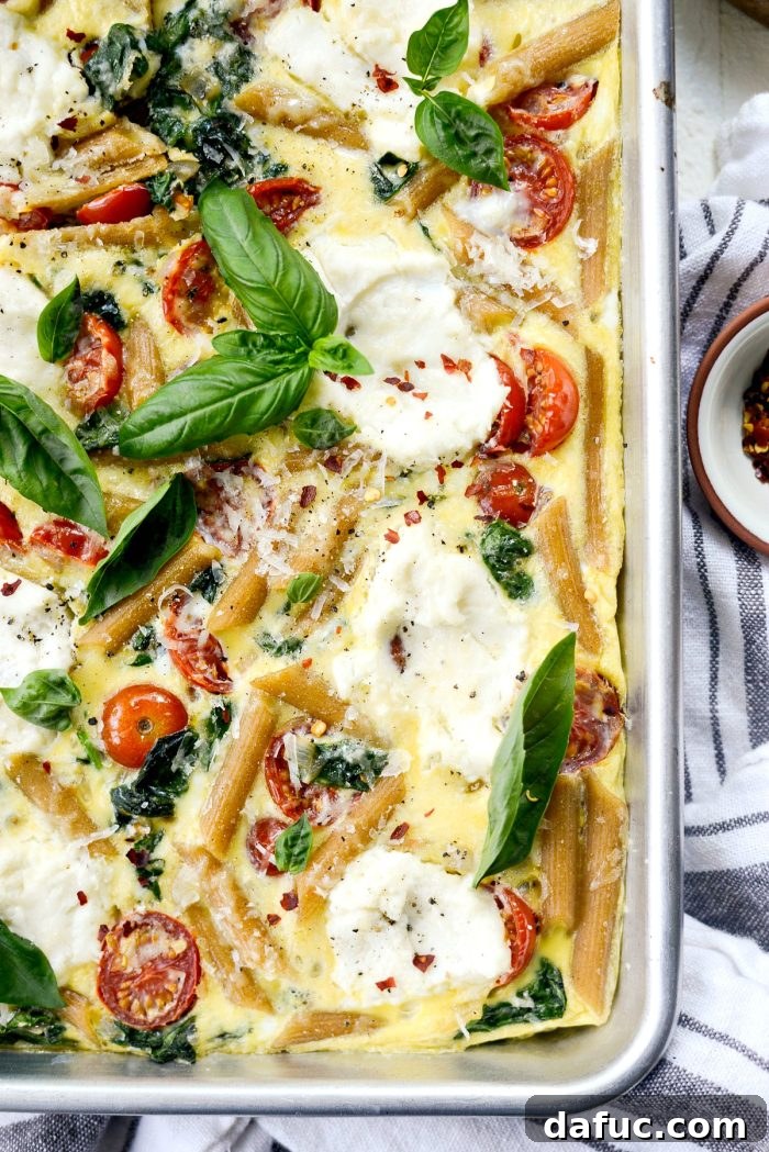 Mediterranean Sheet Pan Pasta Frittata 15 Multiple slices of Sheet Pan Spinach Tomato Ricotta Pasta Frittata on a serving platter.