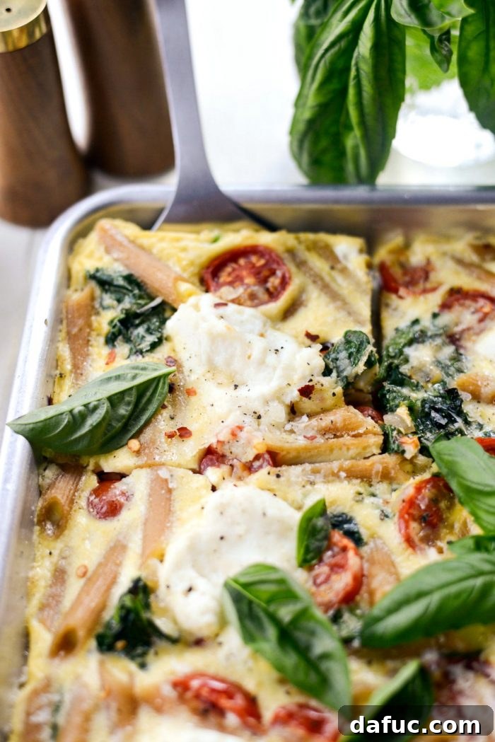 Mediterranean Sheet Pan Pasta Frittata 17 Final plated slice of Sheet Pan Spinach Tomato Ricotta Pasta Frittata with a fork.