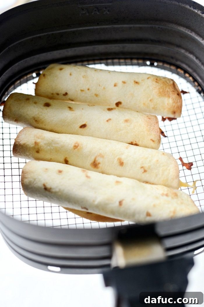 Zesty Air Fryer Salsa Chicken Taquitos 12 Golden brown crispy taquitos being removed from the air fryer
