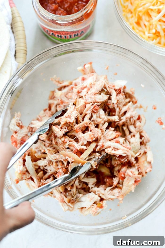 Zesty Air Fryer Salsa Chicken Taquitos 6 A close-up of shredded chicken being mixed with salsa in a bowl