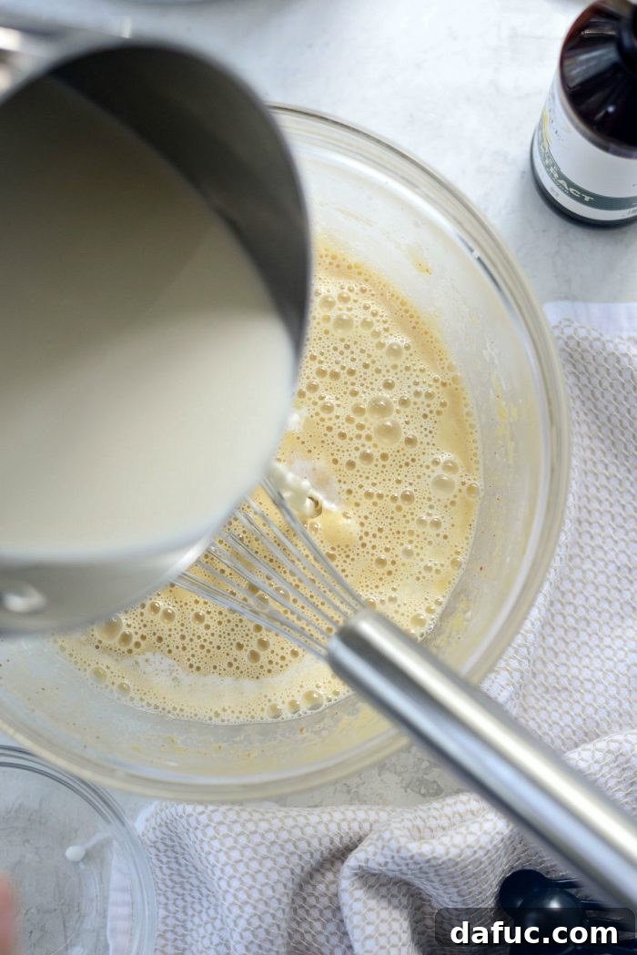 Golden Brown Butter Indulgence 10 Slowly pouring hot cream and milk into the whisked egg and brown butter mixture to temper it.