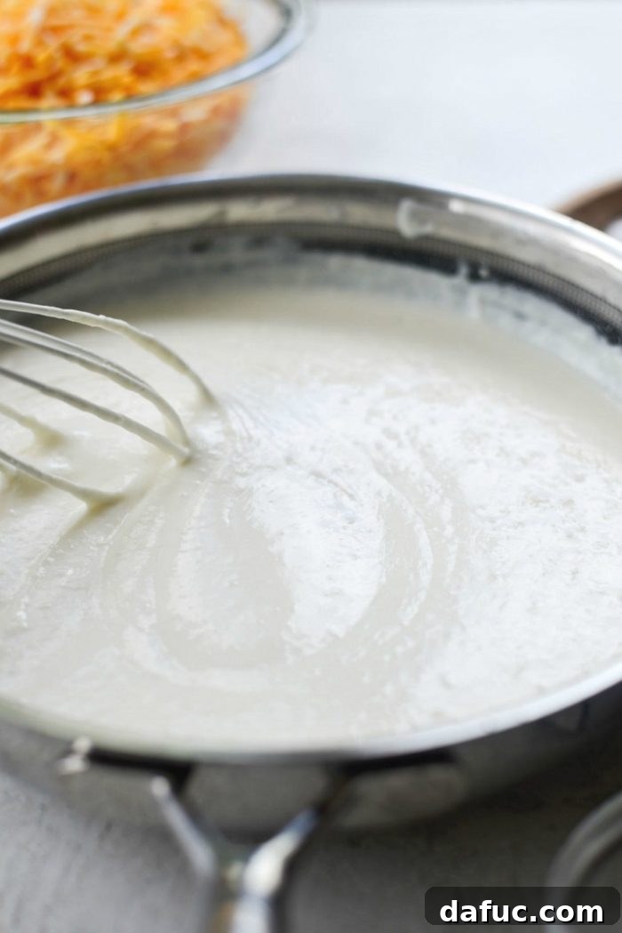 Slowly Pouring Half & Half into Roux for Creamy Mac and Cheese Sauce