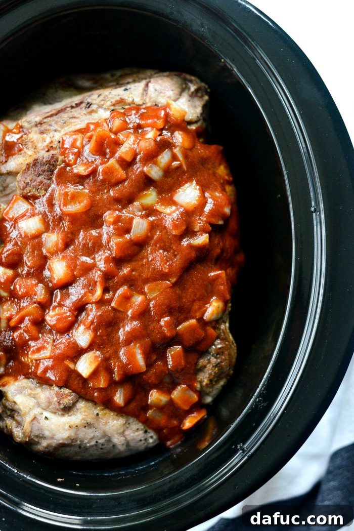 Pouring saucy onions over pork shoulder in slow cooker