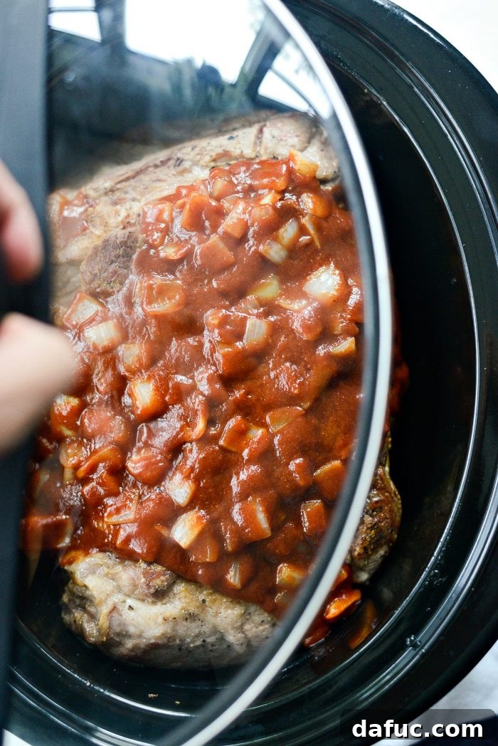 Covered slow cooker with pork and sauce cooking