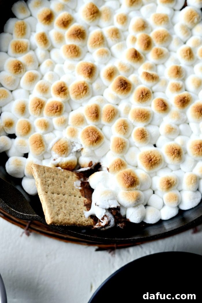 Gooey Campfire Skillet Dessert 10 Skillet S'mores Dip baking in the oven, marshmallows beginning to turn golden brown.