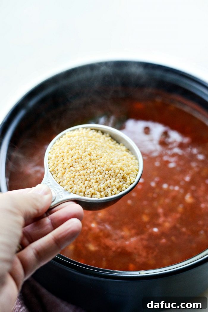 Ancini de pepe pasta cooking in the simmering Beef Tomato Soup, absorbing the flavorful broth.