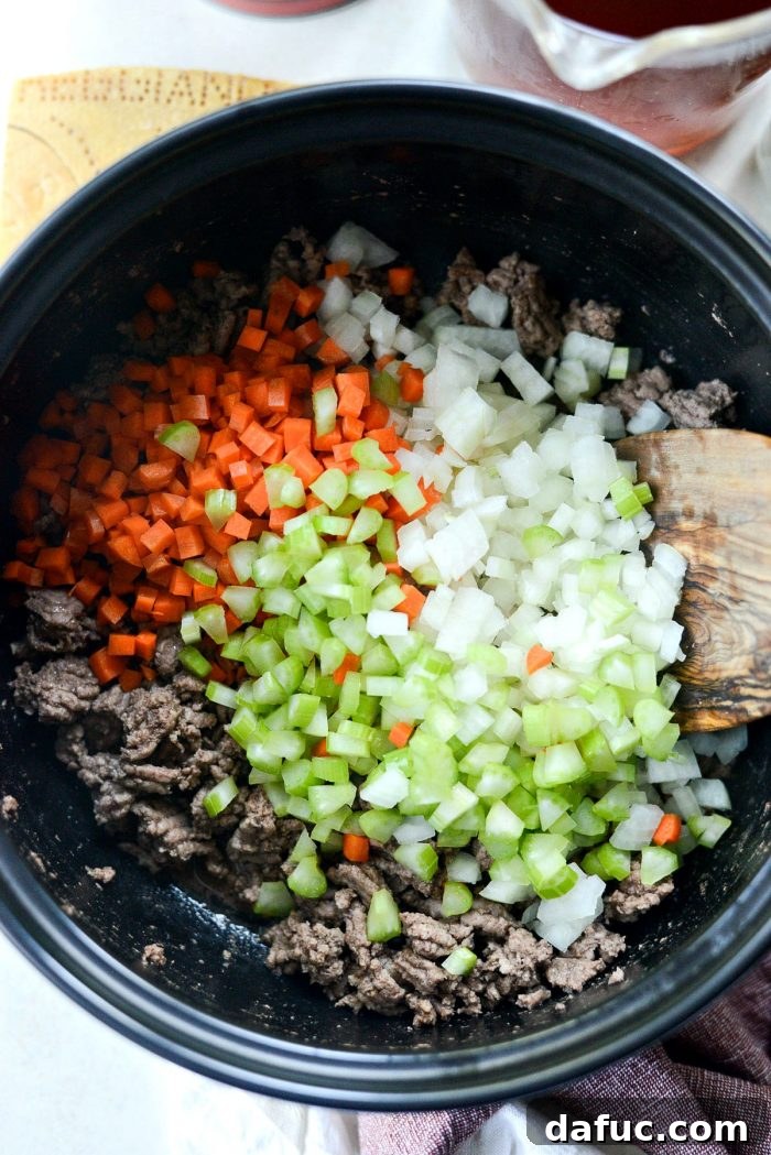 Finely diced yellow onion, carrots, and celery on a cutting board, ready for sautéing for the soup.