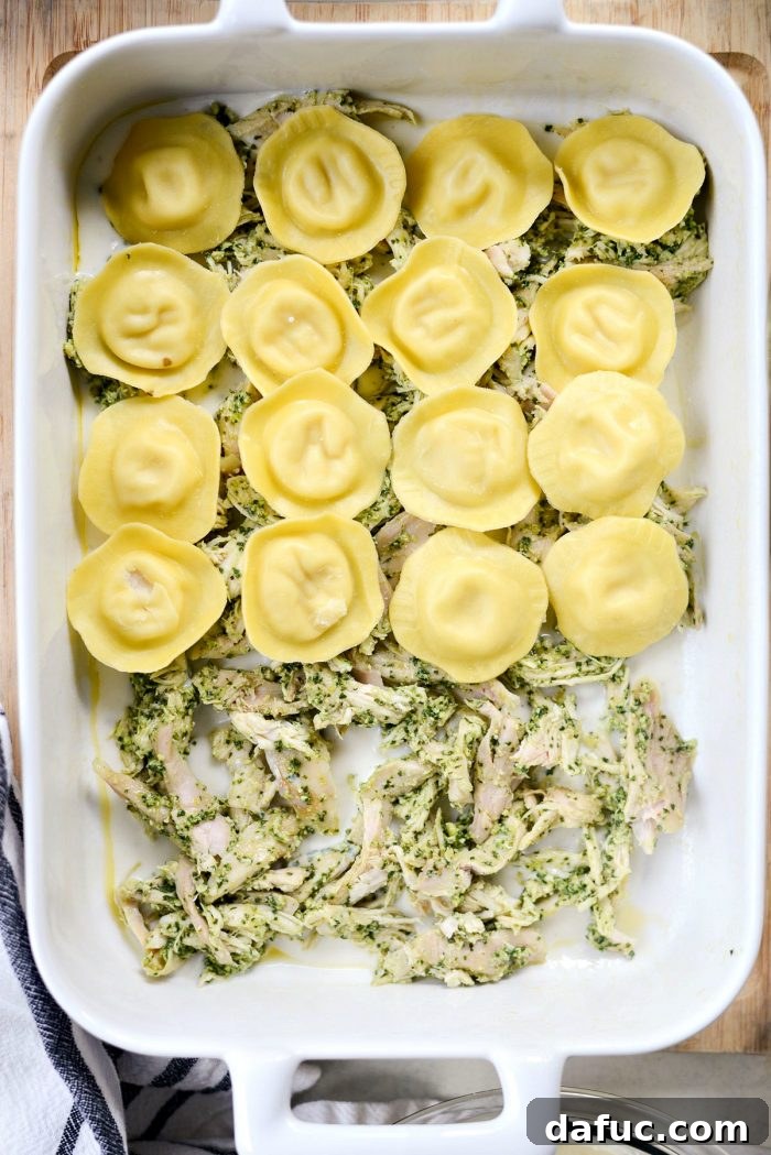 Pesto Chicken Ravioli Lasagna Bake 11 First layer of béchamel sauce and pesto chicken in baking dish