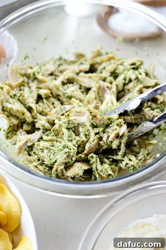 Pesto Chicken Ravioli Lasagna Bake 7 Shredded chicken being tossed with basil pesto in a mixing bowl