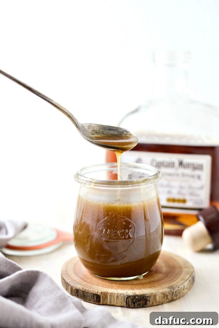 Rich Homemade Butter Rum Sauce drizzled over dessert, showcasing its luxurious texture and golden color. SimplyScratch.com recipe for versatile dessert topping.