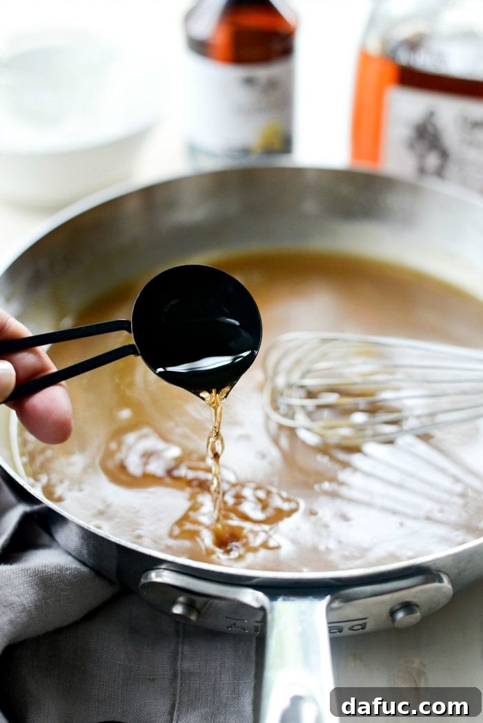 Removing the saucepan from heat and stirring in dark rum and vanilla extract for the finishing touches of the sauce.