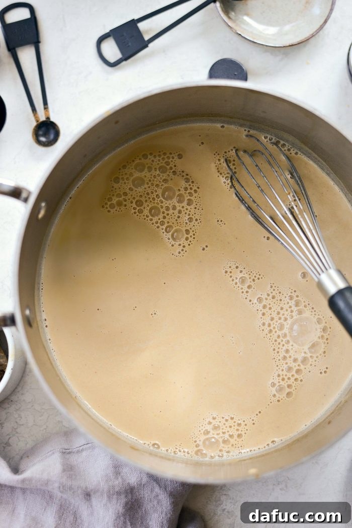 Cozy Pumpkin Chai Dream 12 Milk being frothed in a small saucepan with a whisk
