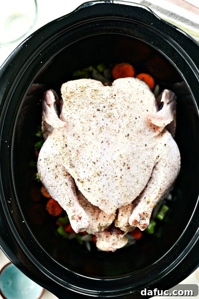 Whole chicken placed on vegetables in slow cooker