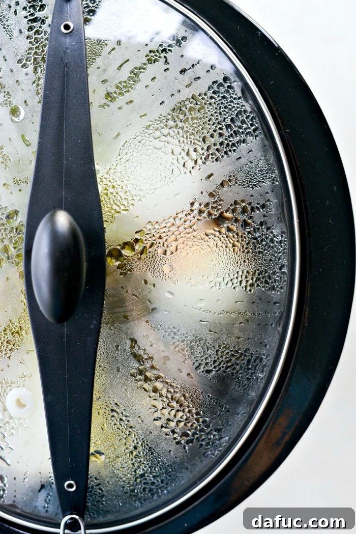 Low & Slow Chicken Broth 11 The slow cooker simmering with chicken stock, steam gently rising, promising rich flavors. #simmeringstock #slowcookermagic #kitchenaroma