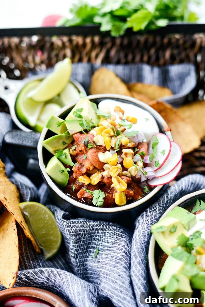 A bowl of Southwest Three Bean Chicken Chili generously topped with avocado, radish, and cilantro