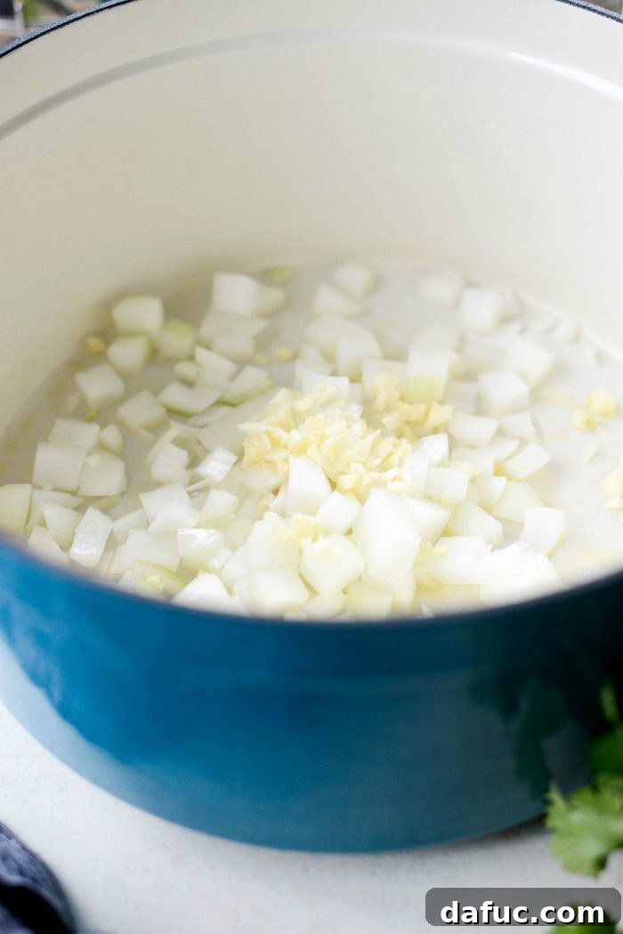 Cooking diced yellow onions and minced garlic in a Dutch oven