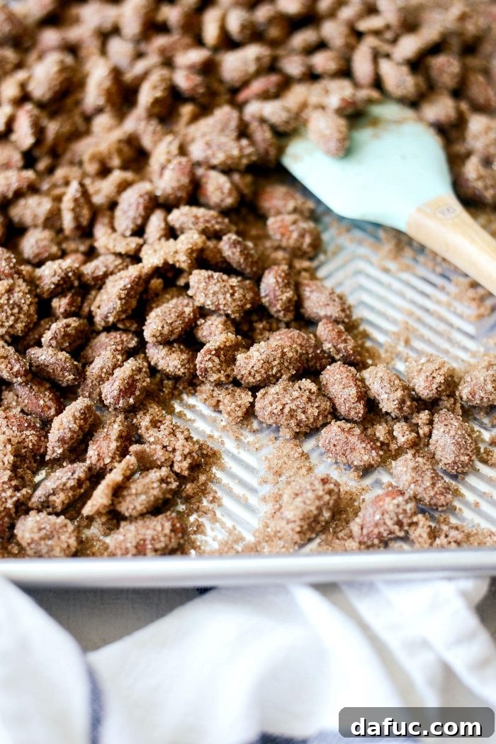 Irresistible Cinnamon Sugar Almonds 13 Cinnamon sugar almonds being tossed on the baking sheet after the first bake, preparing for the second baking phase.