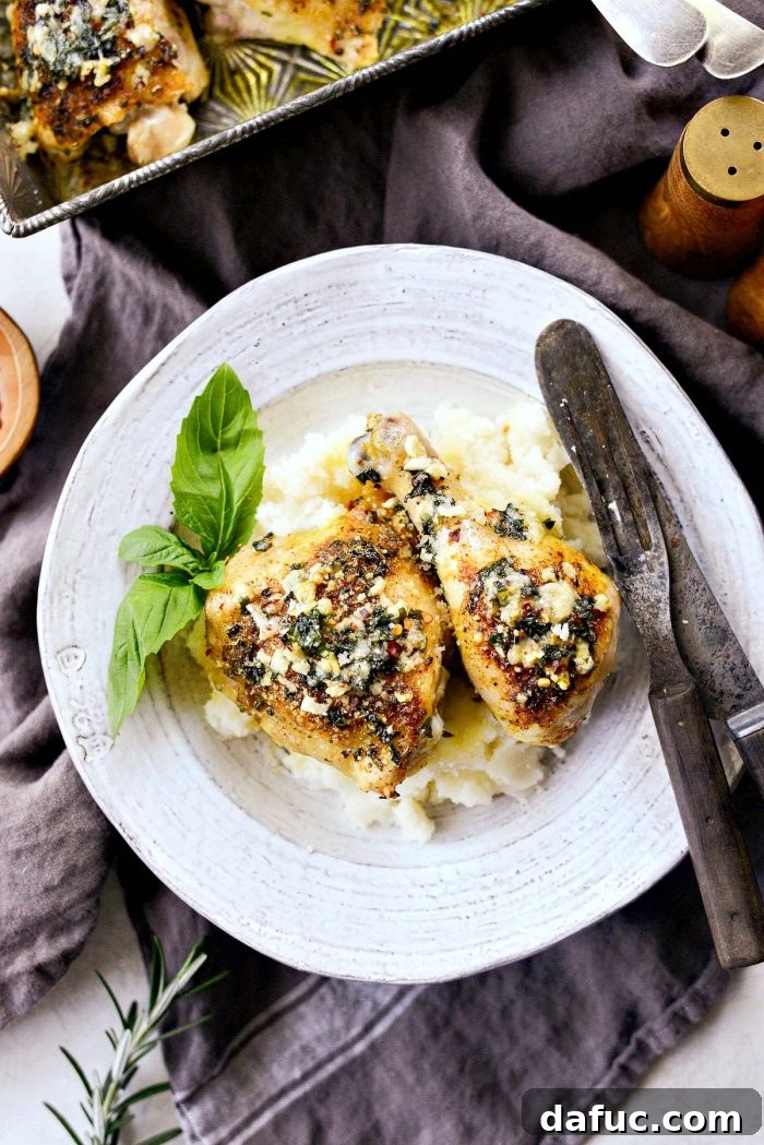 Crispy Garlic Parmesan Baked Chicken 13 Two pieces of Parmesan Garlic Baked Chicken on a serving plate, showcasing the golden, herb-crusted topping.