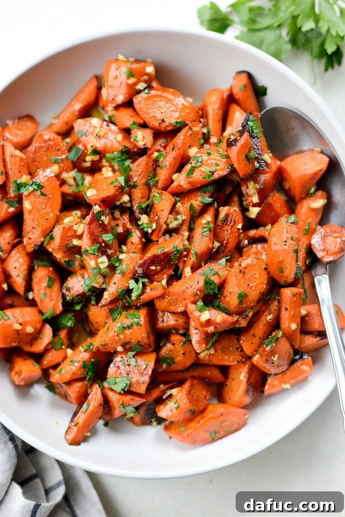 Garlic butter roasted carrots garnished with fresh minced parsley, ready for serving.
