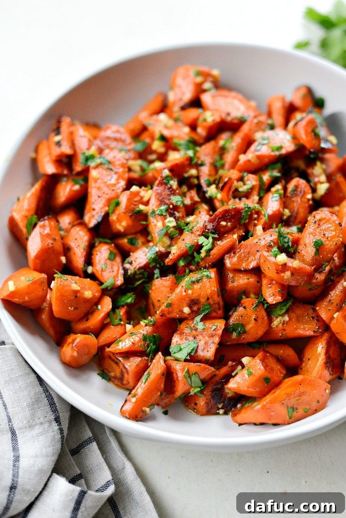 A close-up shot of garlic butter roasted carrots, highlighting the golden caramelization and fresh parsley garnish.
