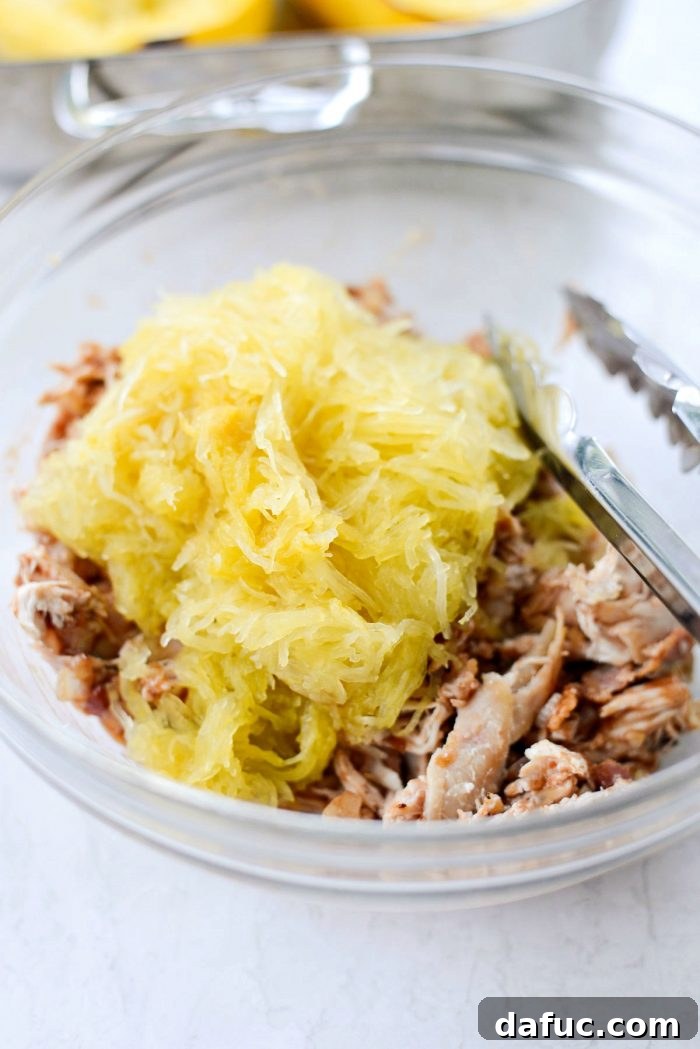 Spaghetti squash strands added to the chicken and bacon mixture in a bowl, ready to be tossed together for the ultimate stuffing.