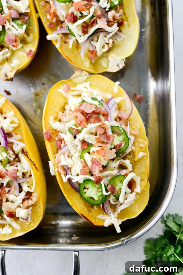 Stuffed spaghetti squash halves topped with shredded Monterey Jack cheese, thin red onion slices, jalapeño slices, and crispy bacon.