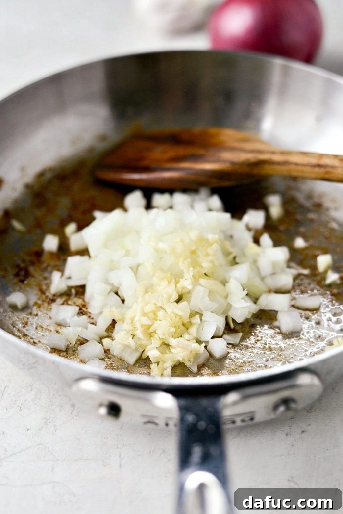 Sautéed onions and garlic in a skillet, fragrant and translucent, forming the aromatic base for the spaghetti squash filling.