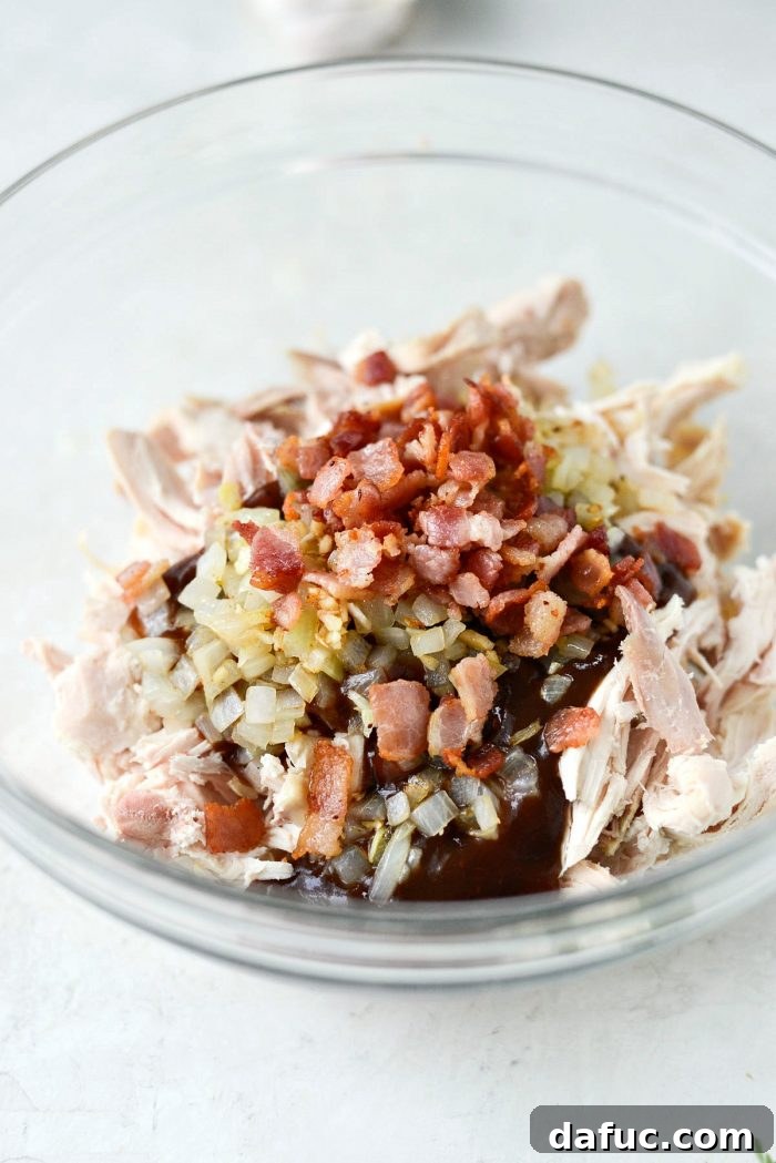 Shredded cooked chicken, BBQ sauce, sautéed onions, garlic, and crispy bacon combined in a mixing bowl for the spaghetti squash filling.