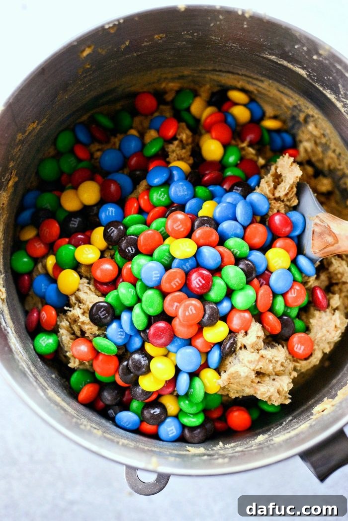 Adding M&Ms to the cookie dough mixture