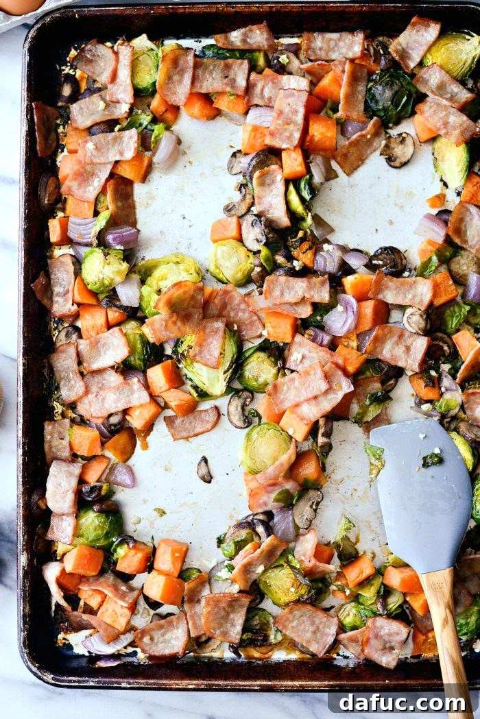 Close-up of the breakfast hash with four wells created in the roasted vegetables and bacon, ready for cracking eggs.
