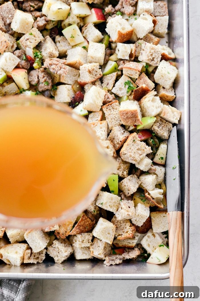 Pouring turkey stock over the mixed stuffing ingredients.