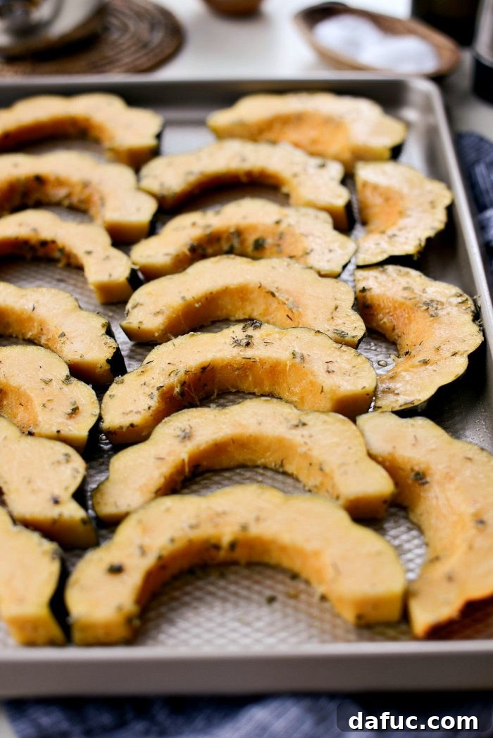Acorn squash slices arranged on a baking sheet, ready for the oven.