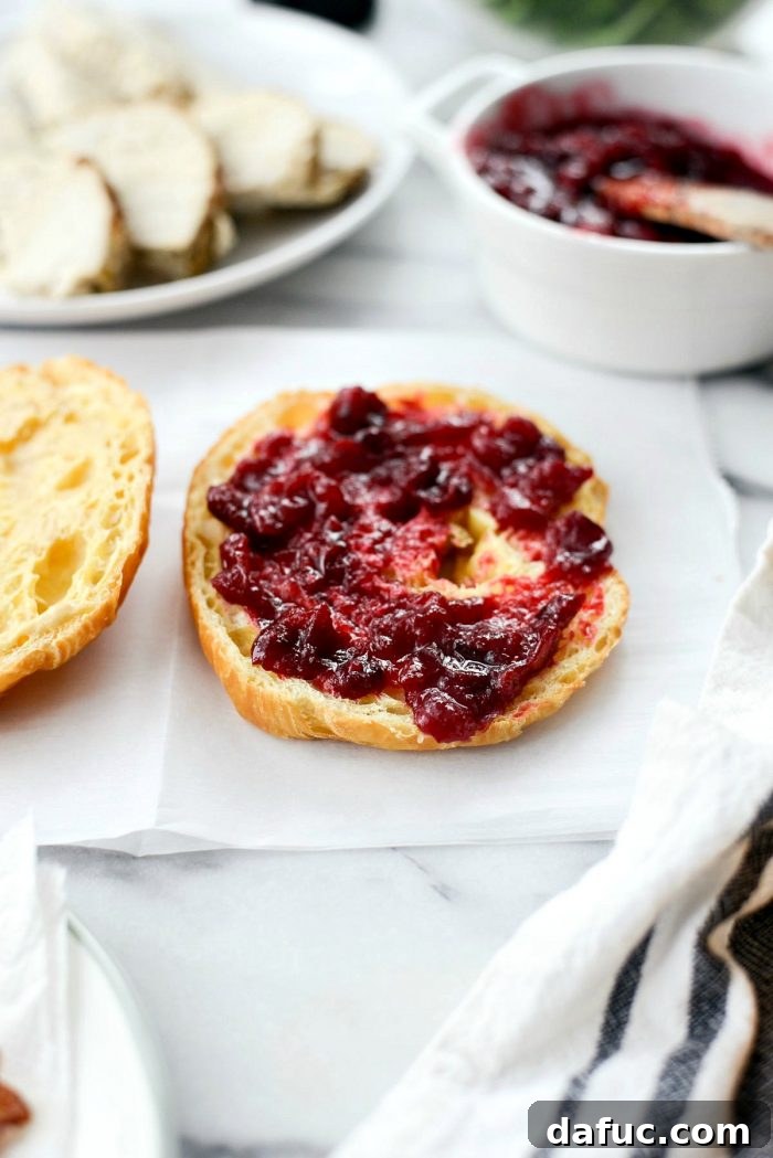 Golden Pressed Turkey Cranberry Croissant 4 Assembling a Turkey Cranberry Croissant Panini: Bottom croissant half spread with cranberry sauce, topped with turkey slices and black pepper.