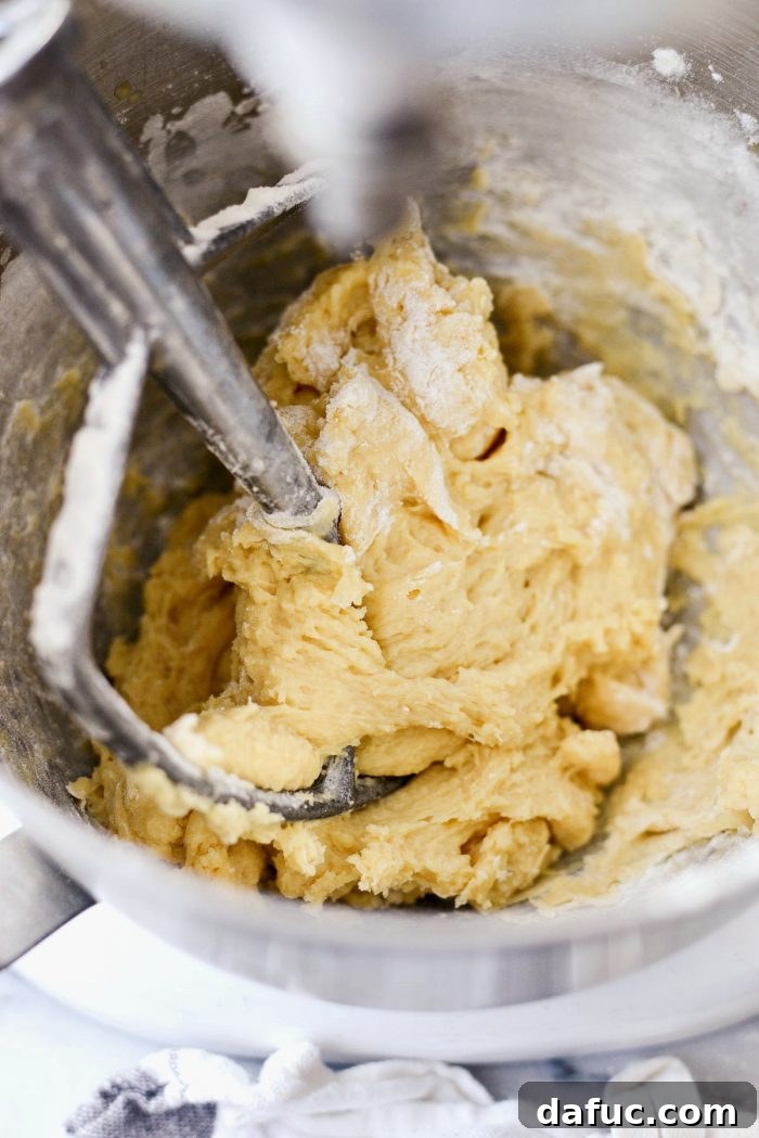Mixing melted butter into the dough mixture in a stand mixer.