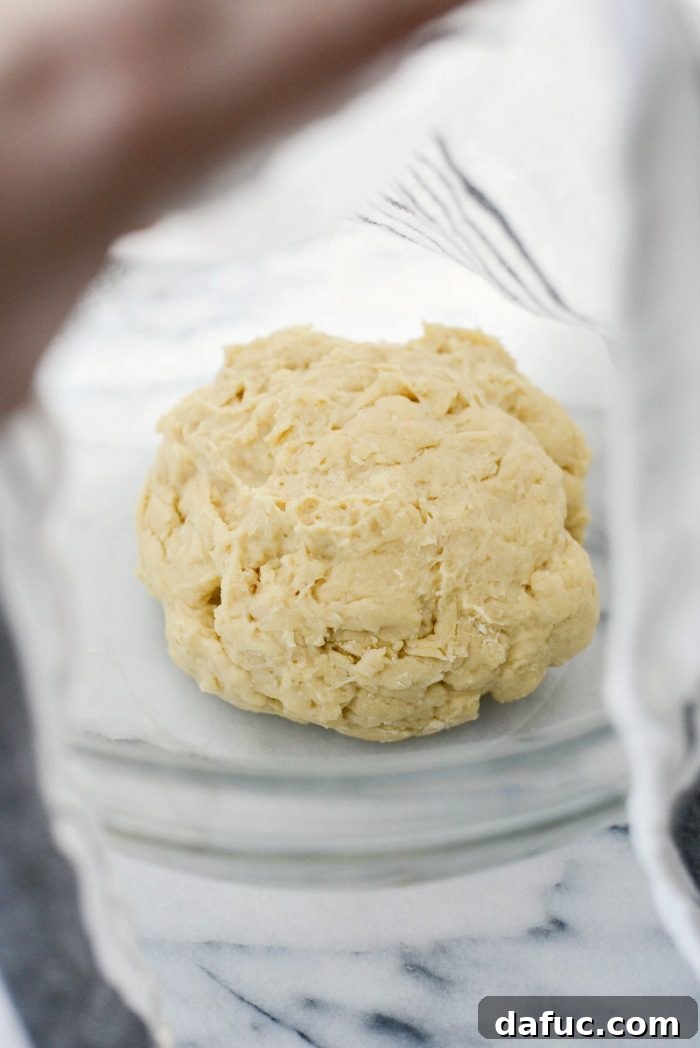 Adding flour mixture gradually to the wet ingredients in a stand mixer to form dough.