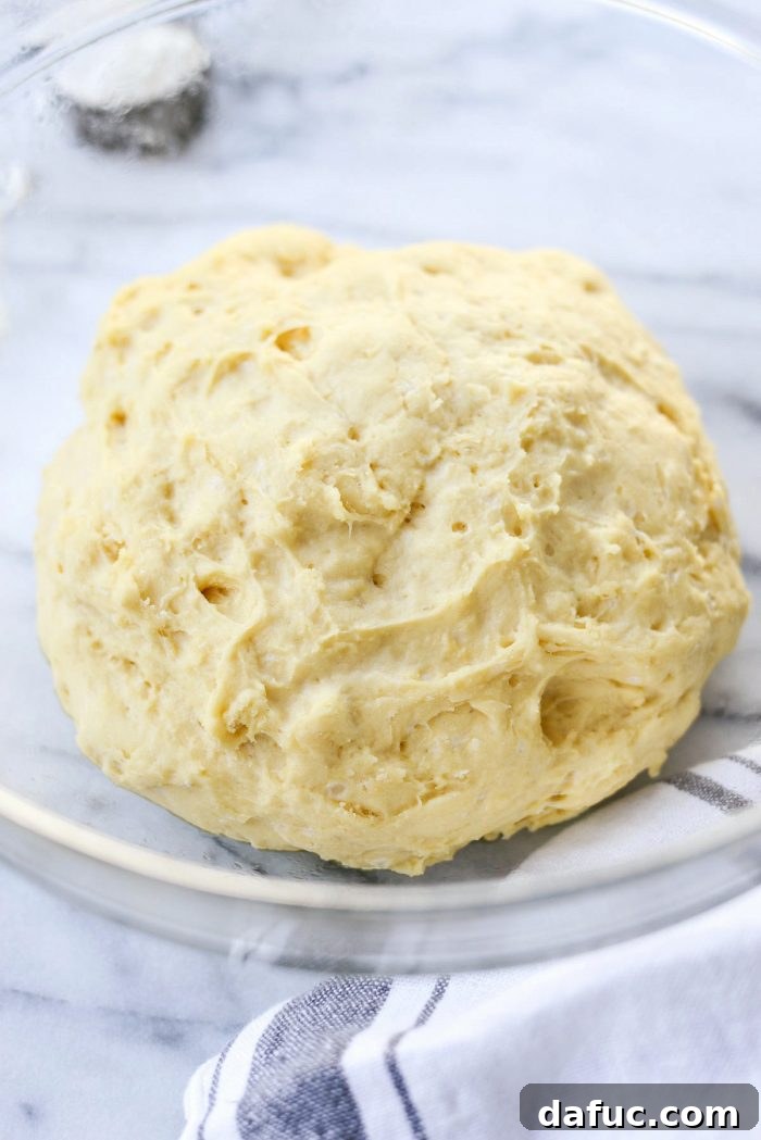 Dough in a lightly oiled bowl, covered with a kitchen towel for the first rise.