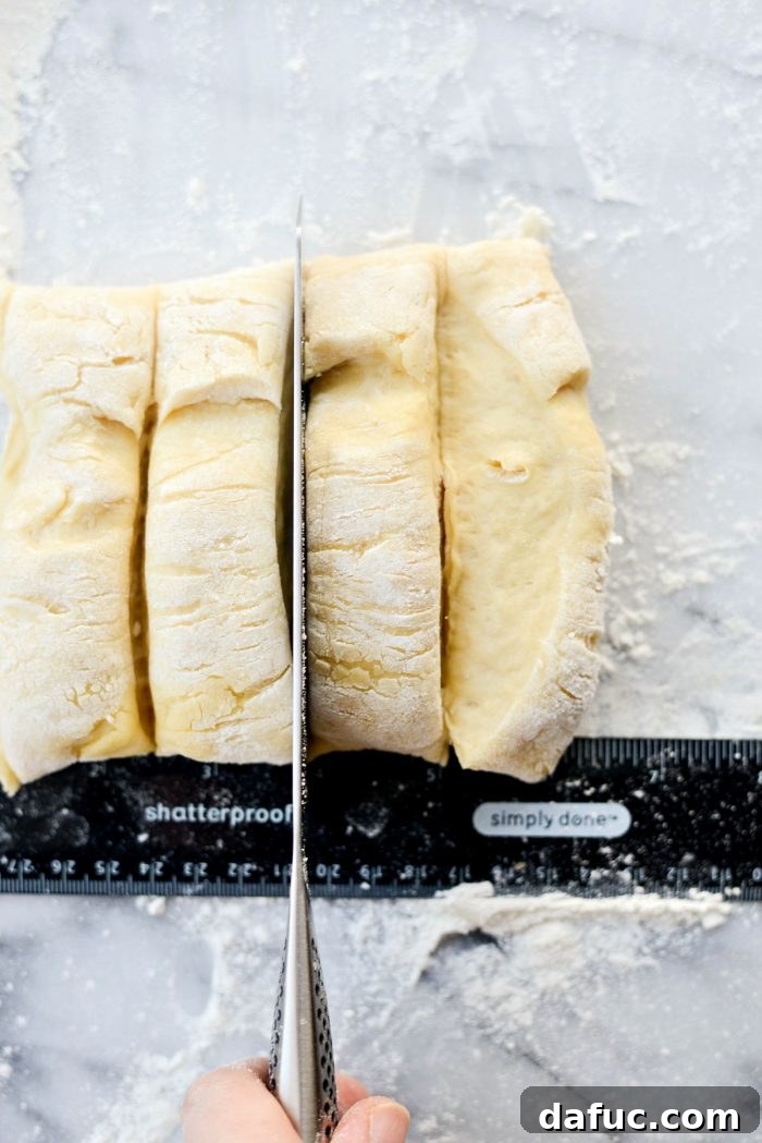 Shaping the dough into a log on a floured surface for cutting into individual rolls.